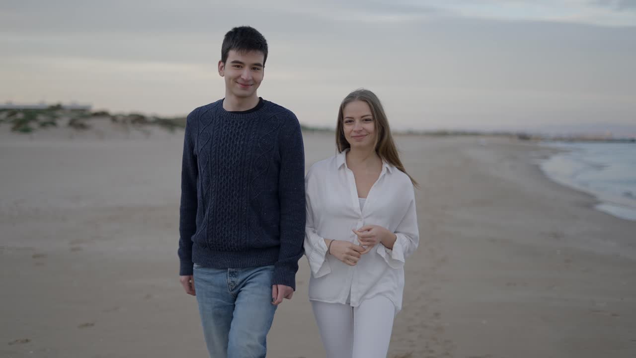 해가 지는 동안 해변을 고 있는 부부