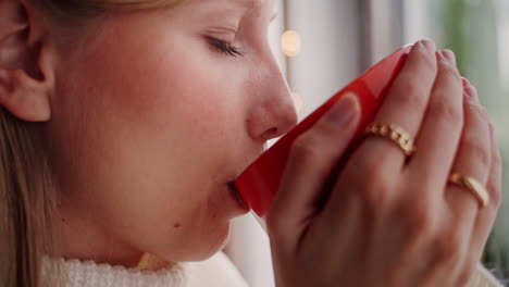 ultra primer plano de una mujer rubia bebiendo café de una gran taza naranja