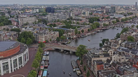 amsterdam netherlands aerial v40 drone flying along famous amstel river with boats cruising on water canal and over blauwbrug bridge across jodenbuurt and grachtengordel neighborhoods - august 2021