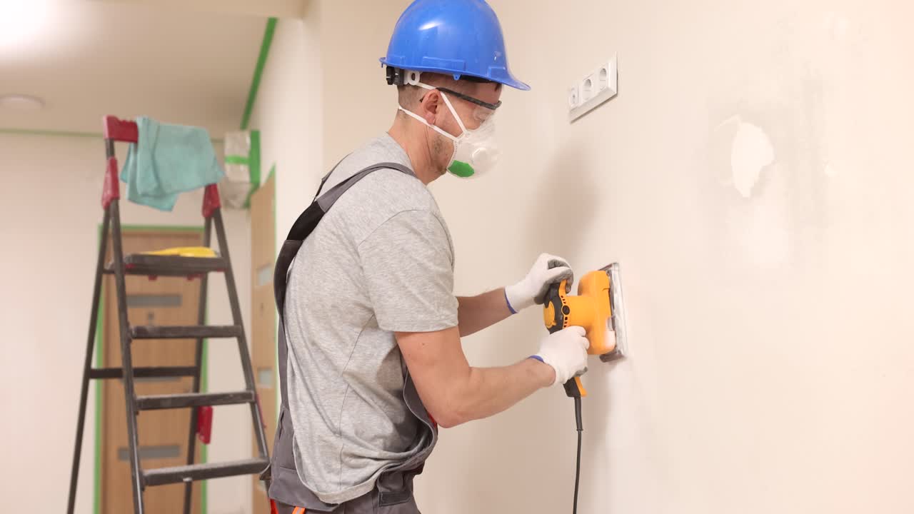 Construction worker sanding wall repair