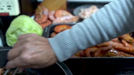 cook removing shrimp from the pan and putting them on a tray