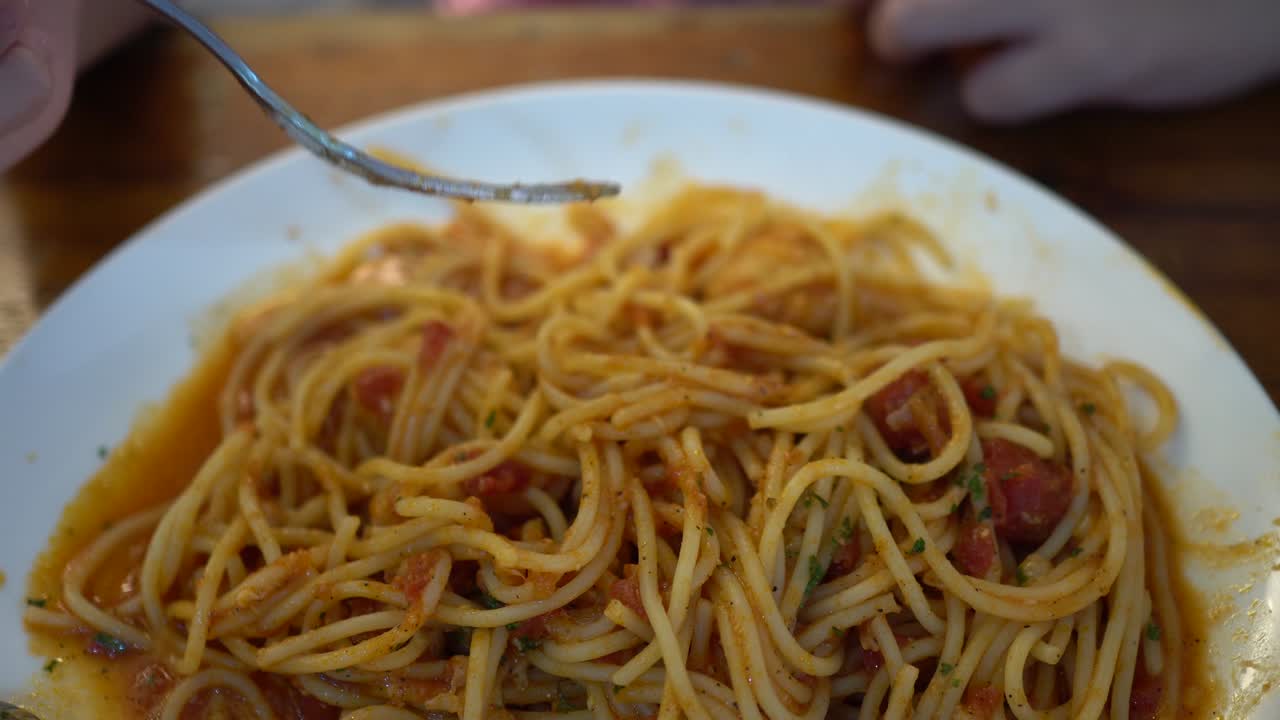 작은 소녀가 레스토랑에서 토마토 해산물 스파게티를 먹습니다.