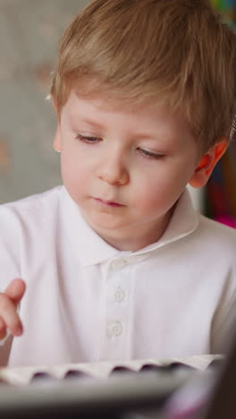 little brother and sister press keys playing music on piano at home closeup. junior schoolgirl with spine injury teaches toddler boy simple chords on keyboard
