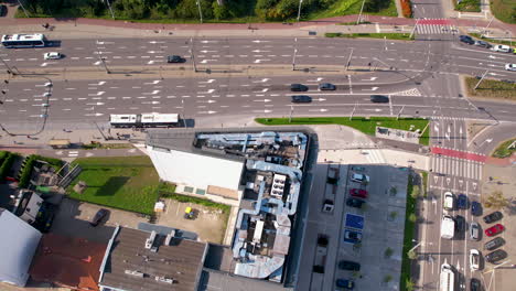 top down aerial - main road intersection - moving cars and public transport - roofs of modern buildings - urban road infrastructure