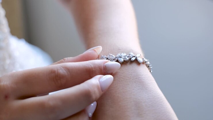 Primo piano di mano di donna che sistema un braccialetto.