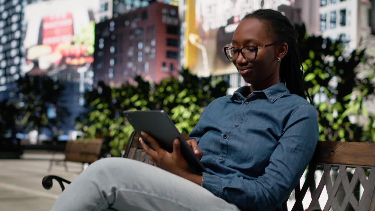 Black digital nomad with tablet, bench in the park downtown, city life relax
