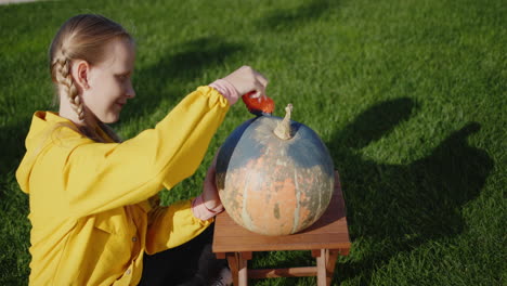 una niña de 10 años pinta calabazas, prepara joyas para halloween