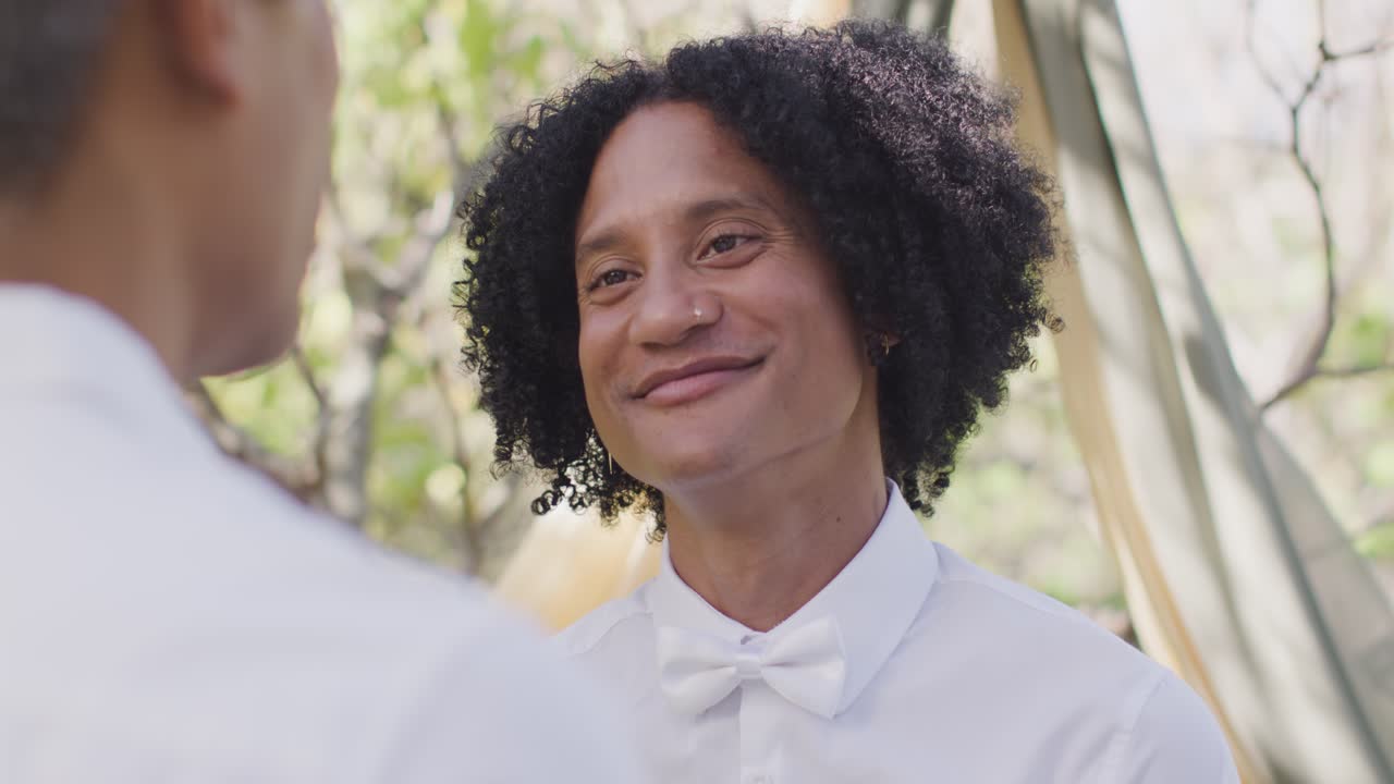 Vertical video: Mid adult man with curly wearing bow tie smiling as partner speaking in garden