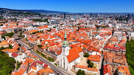 approaching the tower of the church in the old town of bratislava, slovakia. multiple buildings with orange roofs in the historical part of the city. aerial view