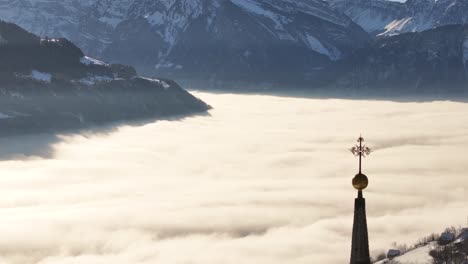 stunning aerial view of walensee, switzerland with breathtaking sea of clouds covering valley, snowy swiss alps, golden sunrise and mystical fog winter landscape.