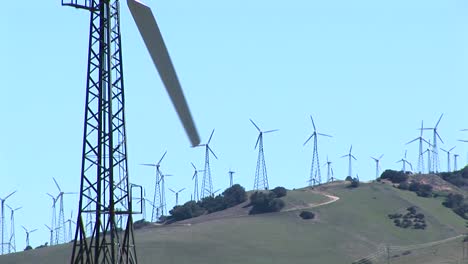 closeup of one wind turbine with numerous turbines in the distance at tehachapi california