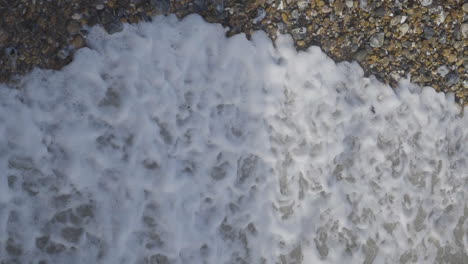 waves coming in and out on stony beach, birds eye view in slow motion