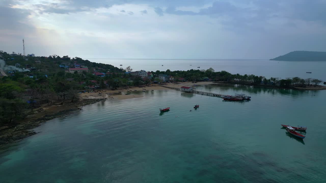 Koh Rong Sanloem island village in Cambodia, featuring turquoise water, pier, boats and tropical jungle. Magic aerial view flight panorama orbit drone