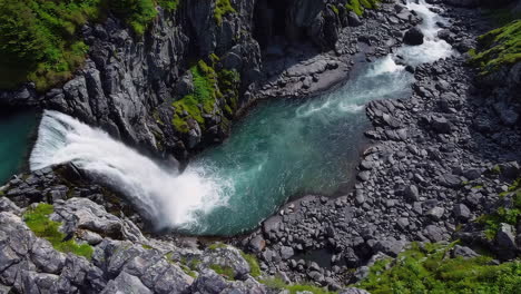 aerial view of a majestic waterfall and turquoise river in a rocky canyon