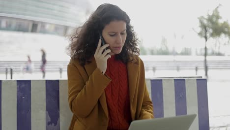 mujer emocional usando un teléfono inteligente y una computadora portátil al aire libre