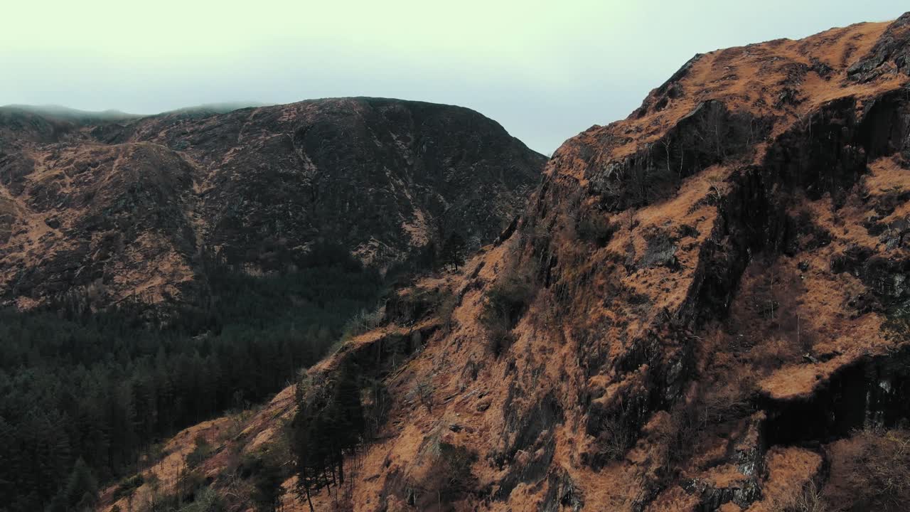 Flying over hill in Gougane National Park revealing forest behind the hill