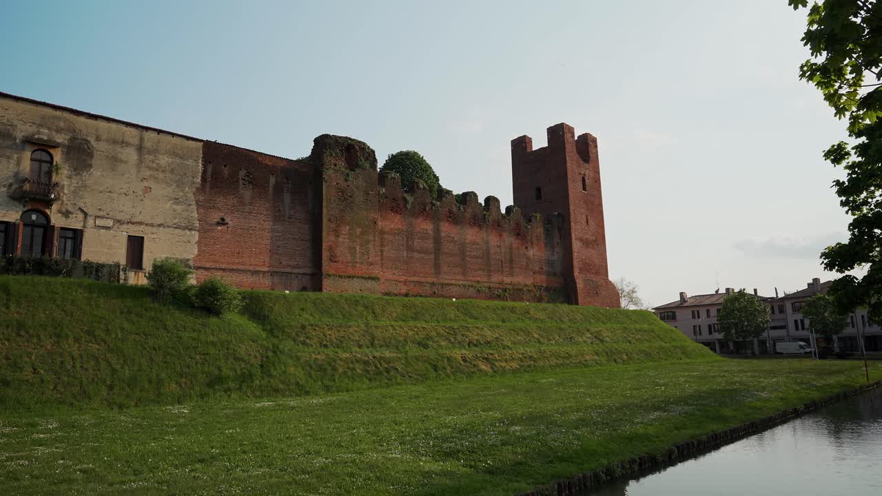 vista estática lateral de las murallas del castillo de castelfranco veneto rodeado de césped y foso