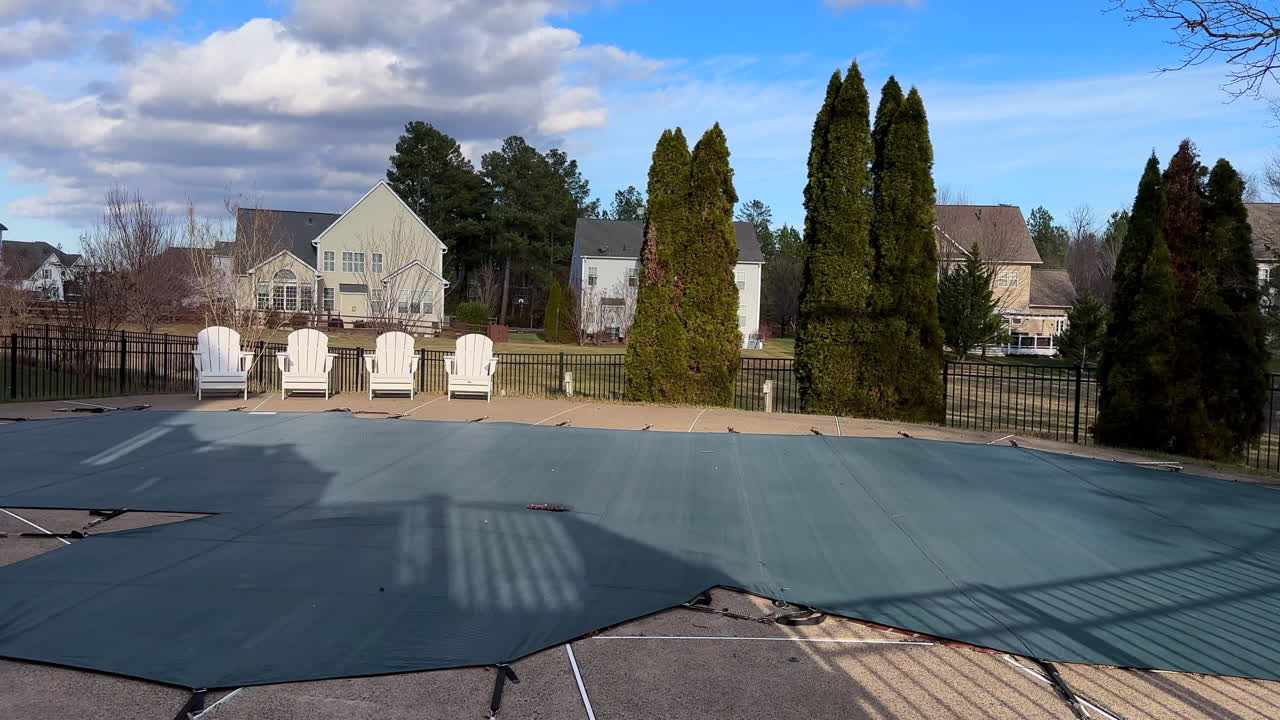 Wide view, residential scene of seasonal swimming pool protection with winterized cover