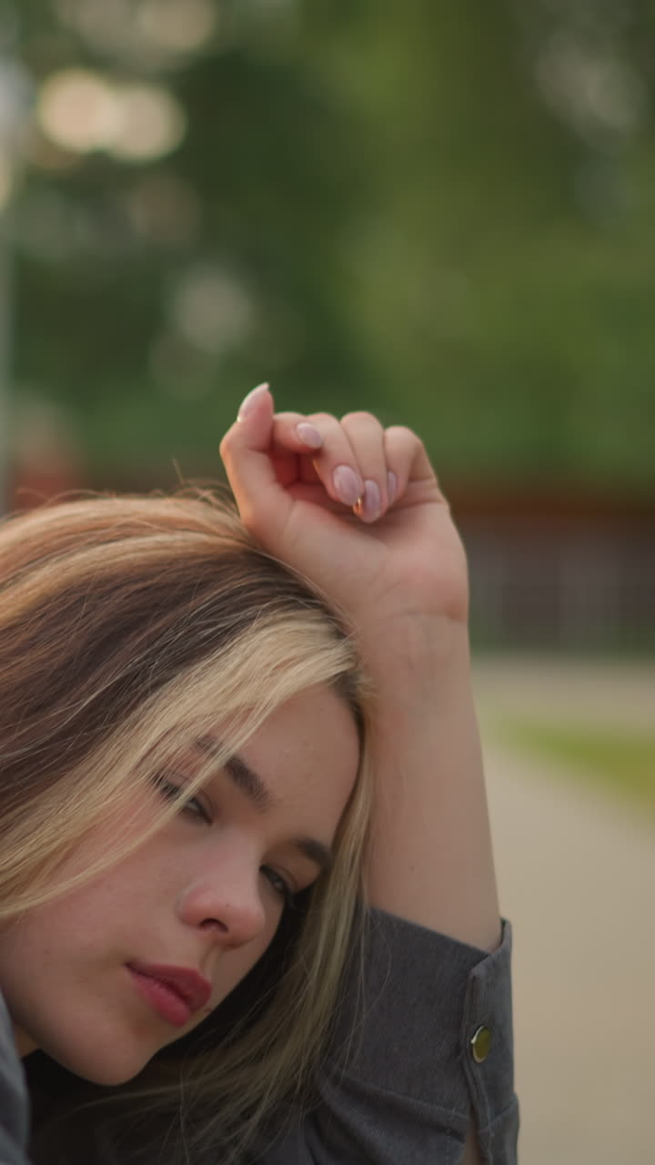 회색 옷을 입은 여자의 클로즈업은 그녀의 머리를 팔 위에 고, 평온한 표정으로 생각에 빠져, 배경이 흐릿하게 남아있는 동안 부드럽게 박인다.