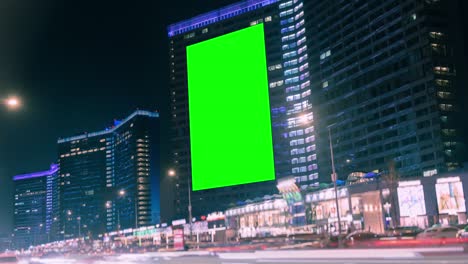 large billboard with green screen for advertising on the modern building with neon lights, timelapse of traffic on busy highway, cyberpunk colors