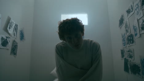 portrait of young man with mental illness sitting in psychiatric room