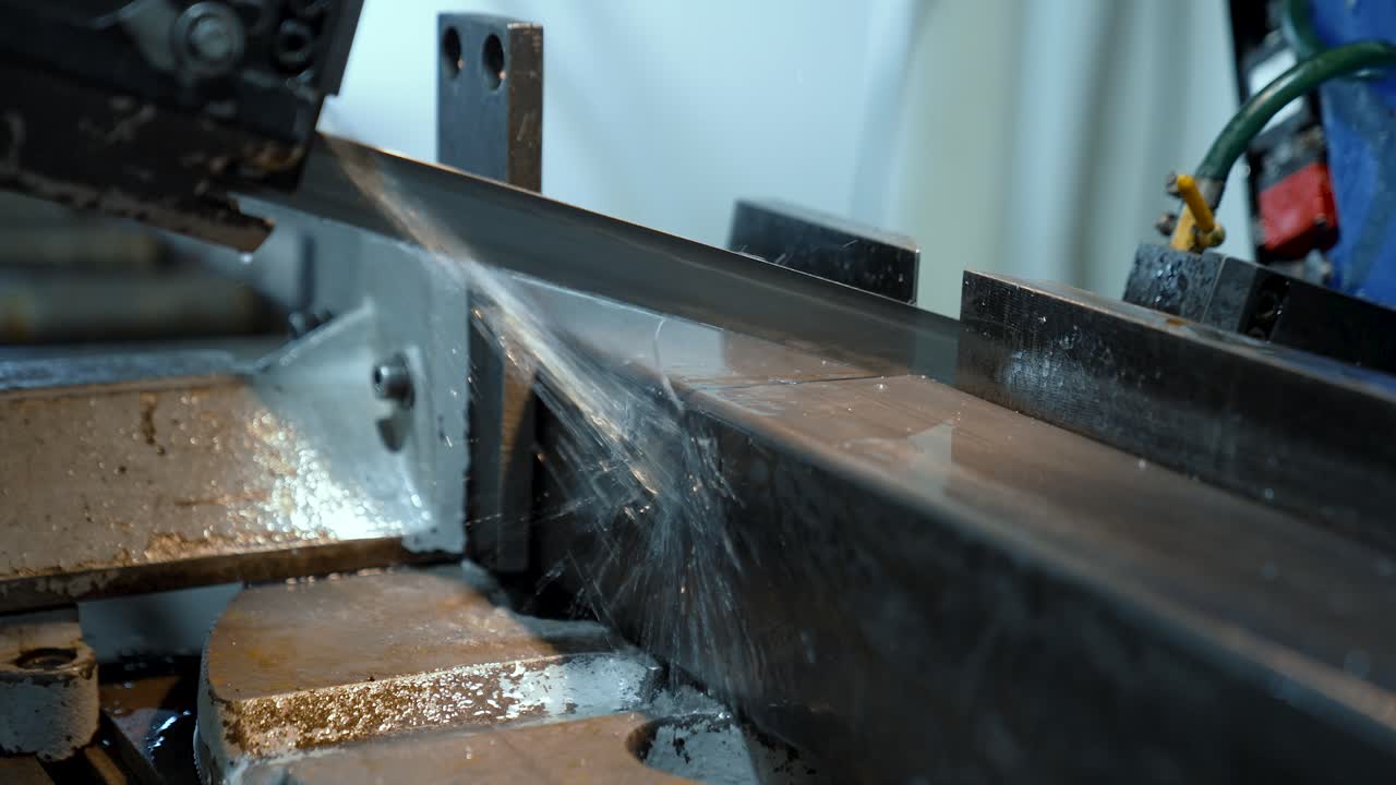 Automatic band saw cuts metal. Machine with coolant supply. Close-up