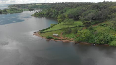 toma aérea orbitando alrededor de una península cubierta de hierba en el río nilo con una exuberante jungla y pescadores a orillas del agua