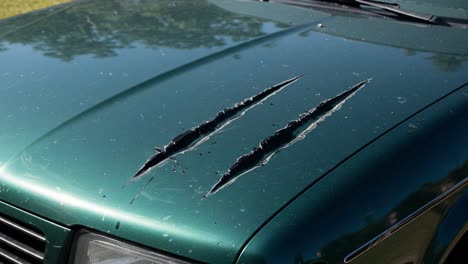 severe damage to vehicle hood: deep scratches and dents captured in two frames, highlighting the impact on the car's exterior and overall condition