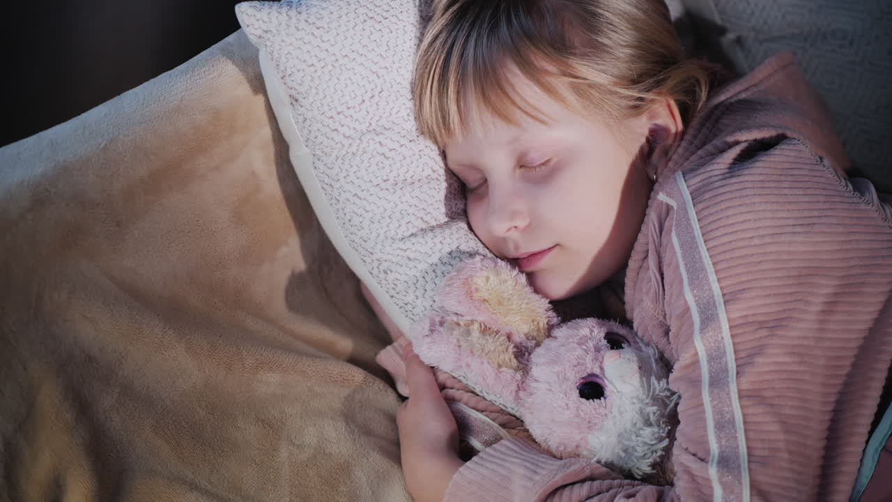 Una ragazza dorme con il suo peluche preferito vista dall'alto