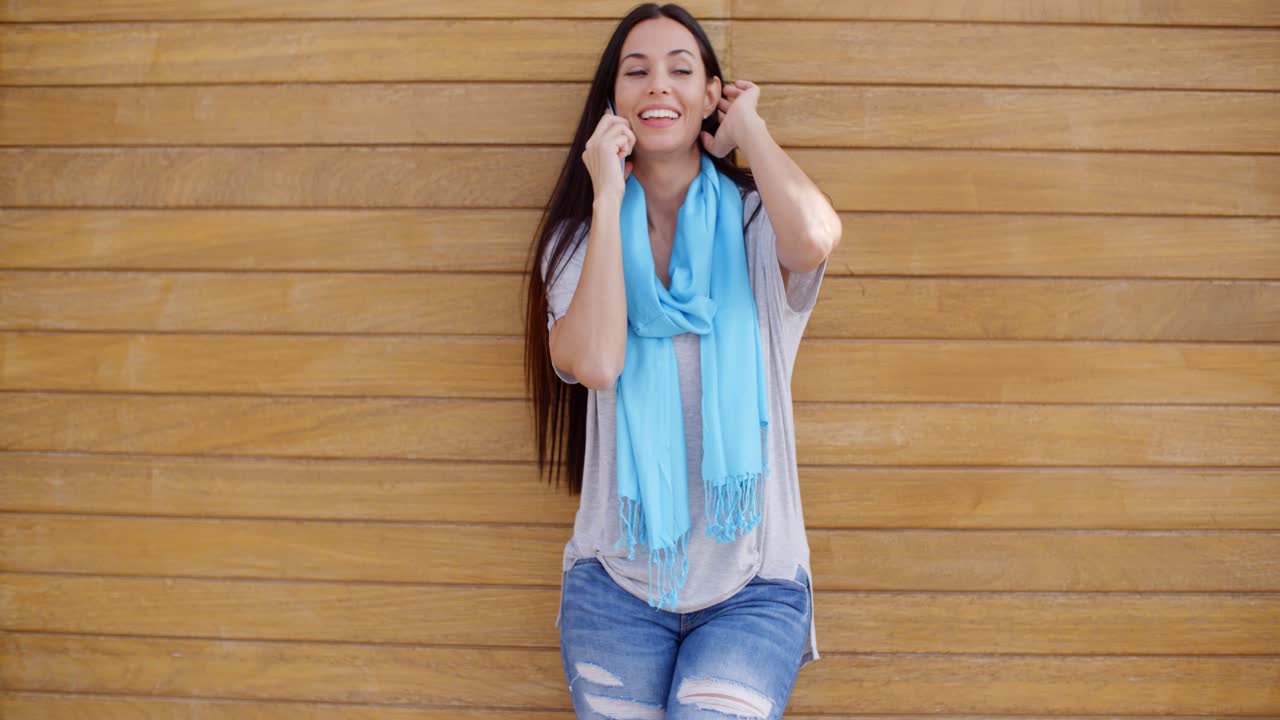 mujer al teléfono y apoyada contra la pared