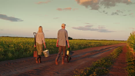 farmers walking through a field at sunset