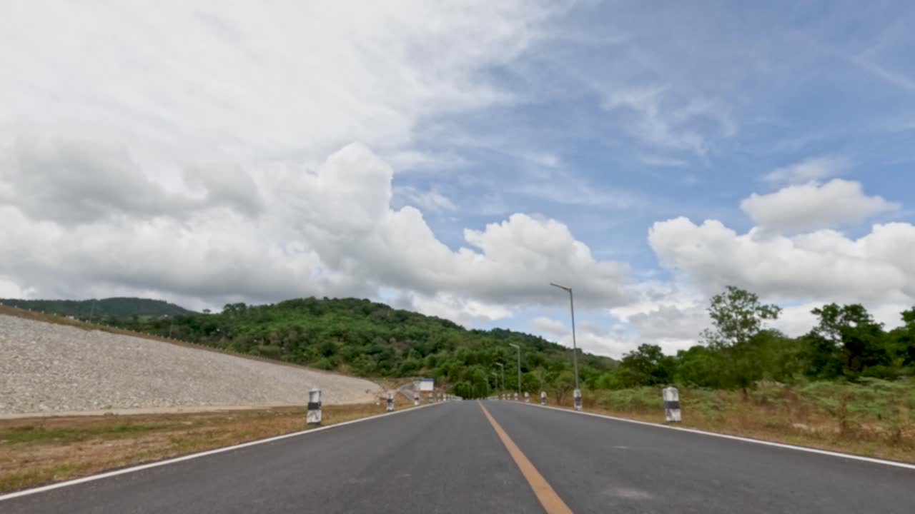 Vehicle travels straight on empty mountain road, daylight, wide angle, steady camera, scenic landscape