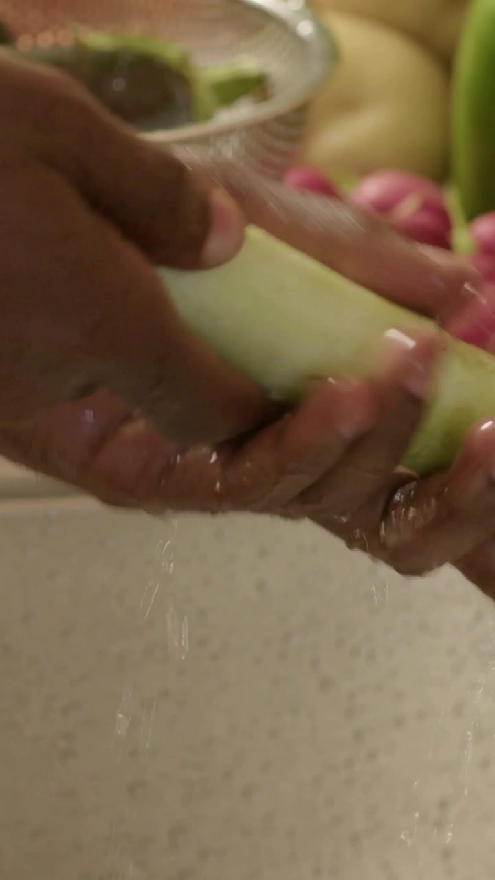 Video verticale: Mani che sciacquano un gambo verde ruotandolo sotto il rubinetto del lavello, poi lo mettono in uno scolapasta per la cottura.