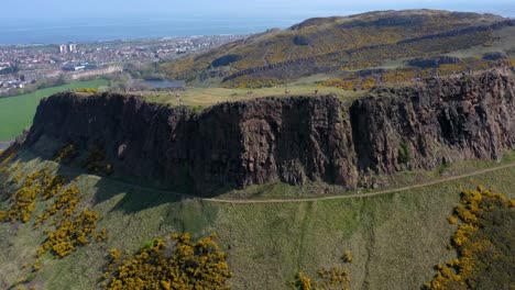 Panning-Around-The-Crags-at-Arthur's-Seat,-near-Holyrood-Parliament,-with-Tourists-Walking-|-Edinburgh,-Scotland-|-4K-at-30-fps