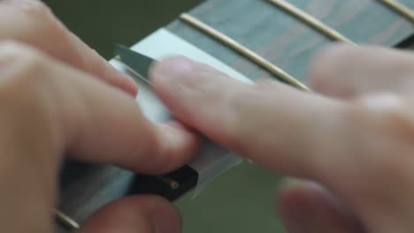 Polishing-Fret-Of-An-Acoustic-Guitar,-Fingerboard-Covered-With-Masking-Tape---close-up