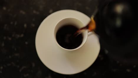 close-up-birds-eye-view-of-coffee-pot-pouring-into-coffee-cup-on-a-marble-countertop