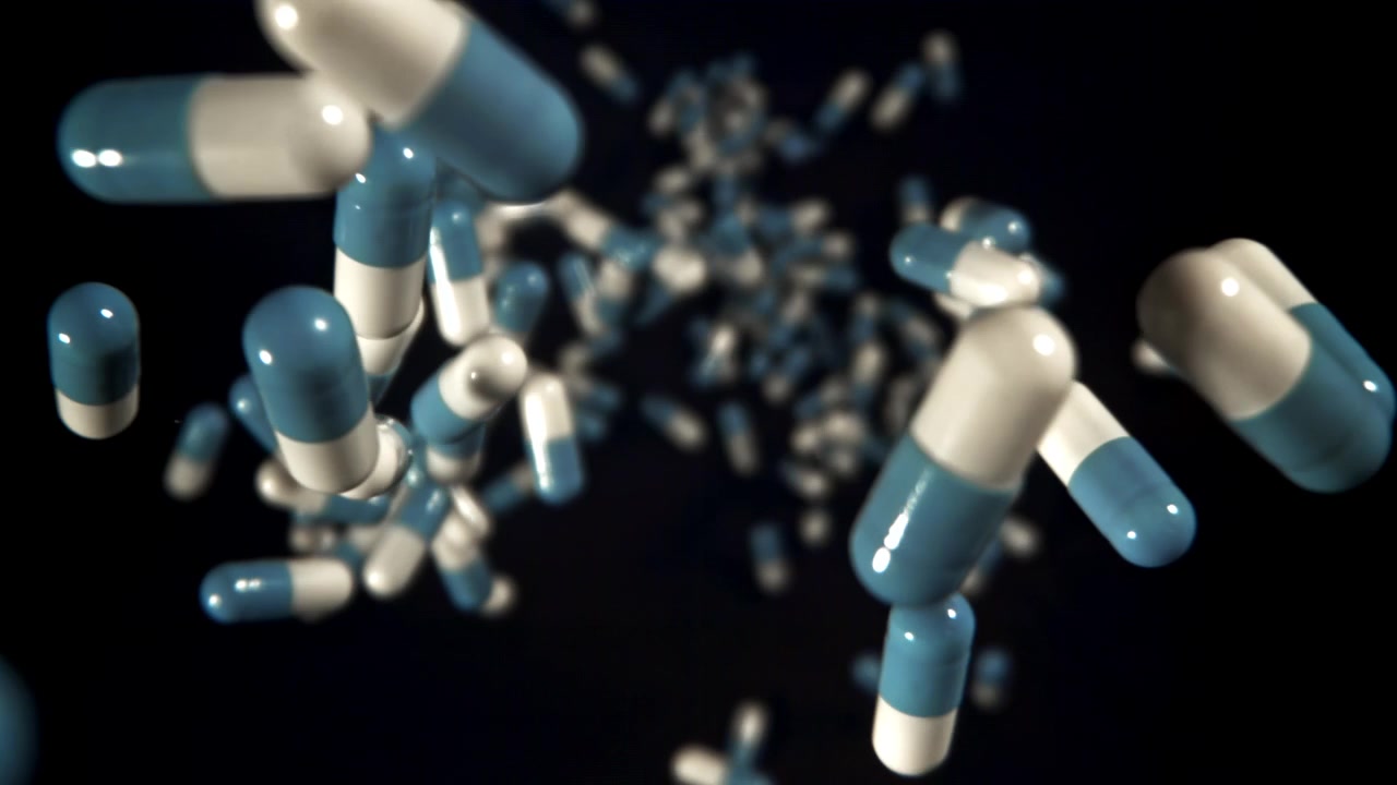 Capsule farmaceutiche che cadono e ruotano nello spazio scuro