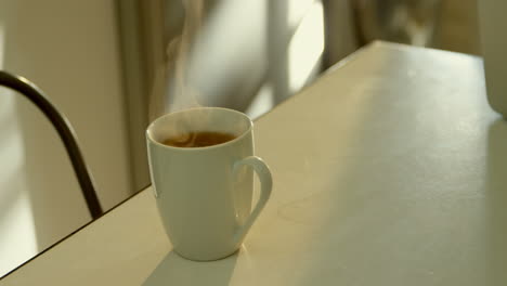 close-up of mug of coffee on dining table in kitchen of comfortable home 4k