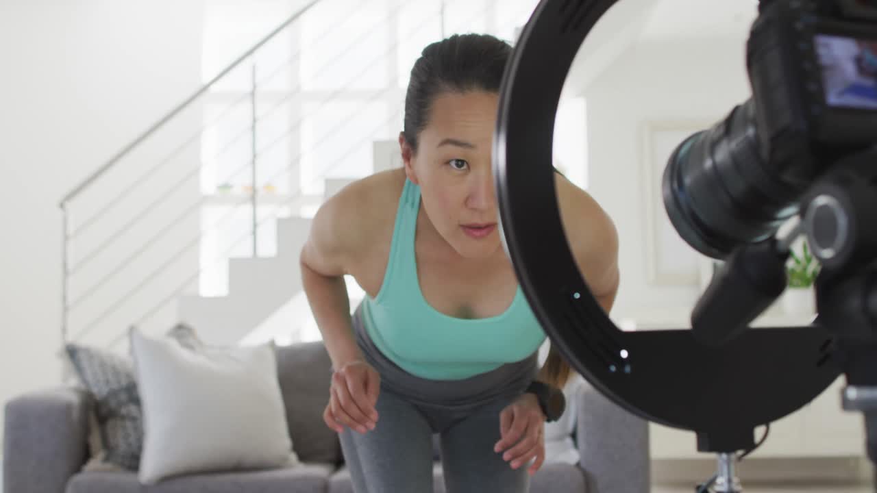 행복 한 아시아 여성 이 집 에서 피트니스 블로그 를 만들기 위해 카메라 를 준비 하고 있다