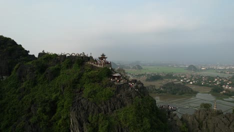 turistas que visitan la famosa estatua de la montaña del dragón mentiroso durante una hermosa puesta de sol en la provincia de ninh binh en el norte de vietnam, revelando una vista panorámica de la ciudad y la cordillera de piedra caliza