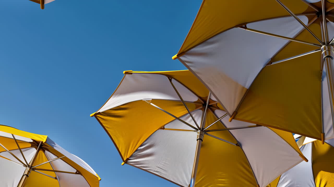 Yellow and white beach umbrellas against a clear blue sky