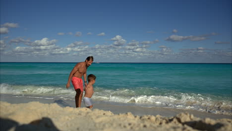 Zeitlupe-Eines-Fitten-Mexikanischen-Latino-Papas,-Der-Mit-Seinem-Sohn-Spielt,-Der-Vom-Wasser-Weg-In-Richtung-Kamera-Rennt,-Lächelt,-Lacht-Und-Spaß-Hat