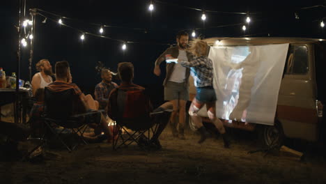 friends watching a movie under the stars in a van
