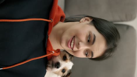 Portrait-of-a-brunette-woman-with-small-dog-Jack-Russell-terrier-on-her-shoulder-looking-to-the-camera