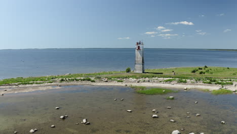 Filmische-Aufnahme-Von-Menschen-An-Einem-Weißen-Leuchtturm,-Die-Kamera-Fliegt-Durch-Einen-Vogelschwarm