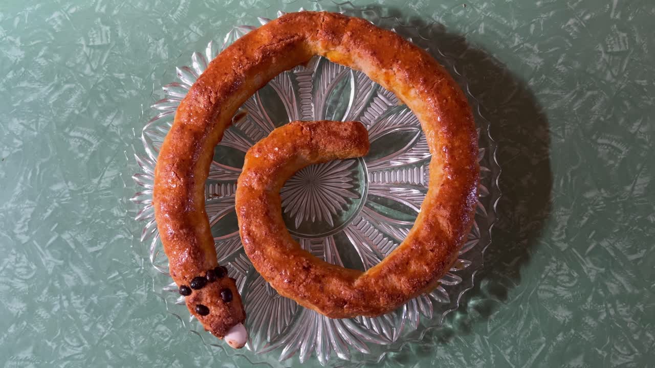 Top-down shot of a freshly baked traditional Italian Christmas cake, the Torciglione or tortiglione, shaped like a snake. For cooking, holiday, or cultural content