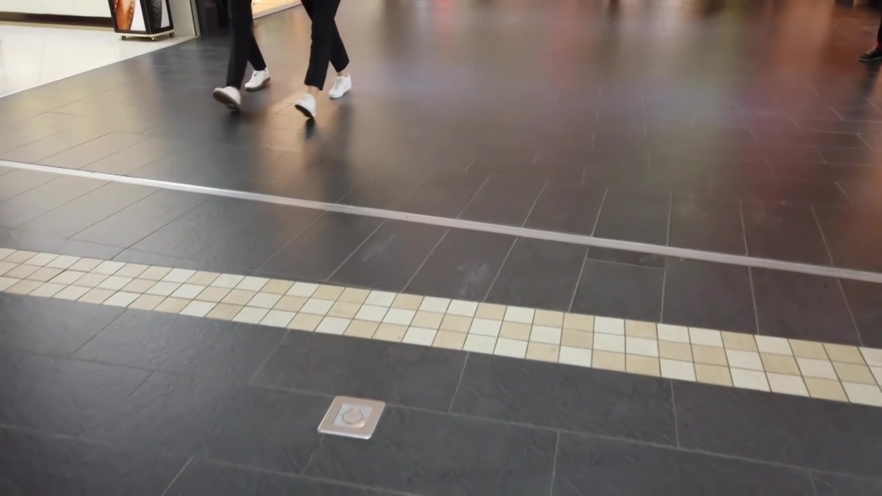 Gulv i indkøbscenter. Mønster fra en flise. Kunder i indkøbscenter