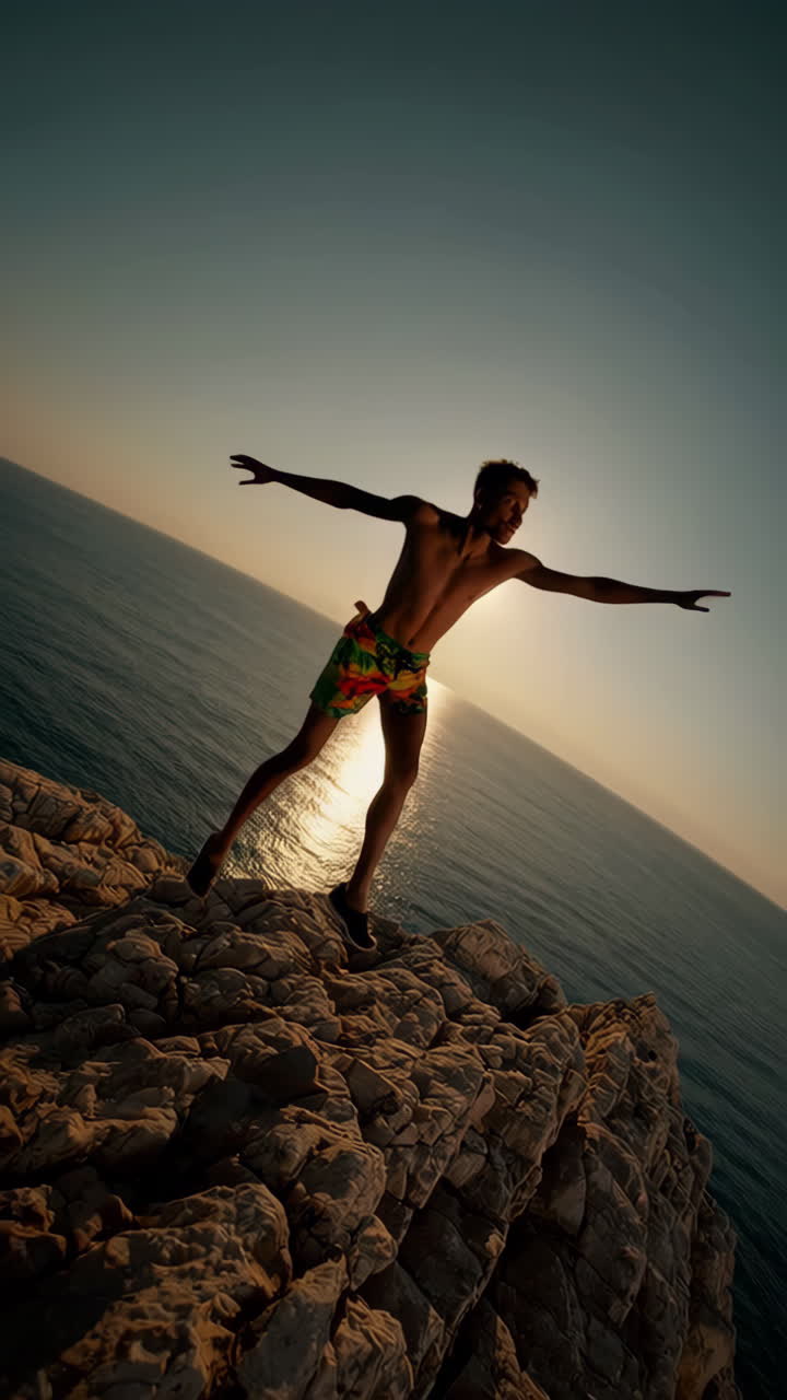 Young Man on Cliff Overlooking Ocean at Sunset