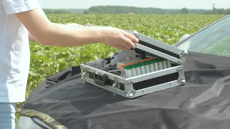 laboratory worker holding professional glassware and testing plant sprouts before harvest in the field.