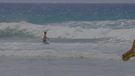 man wading in ocean waves at currumbin beach